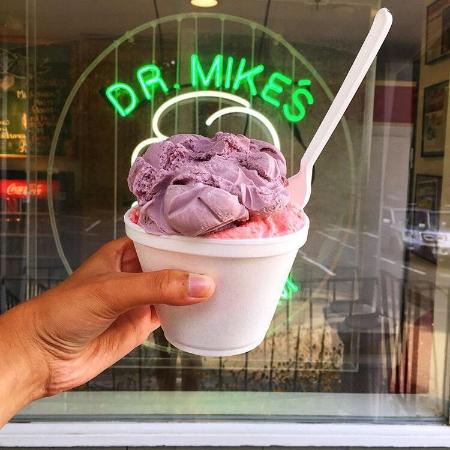 A cup of ice cream held up outside Dr. Mike's